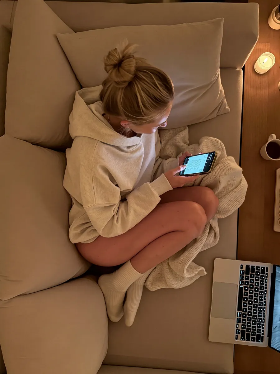 Filling out the application on her phone from the couch (illustrative)